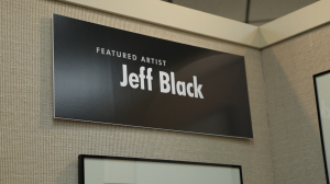 Black placard on the wall with "Featured Artist Jeff Black" in white print