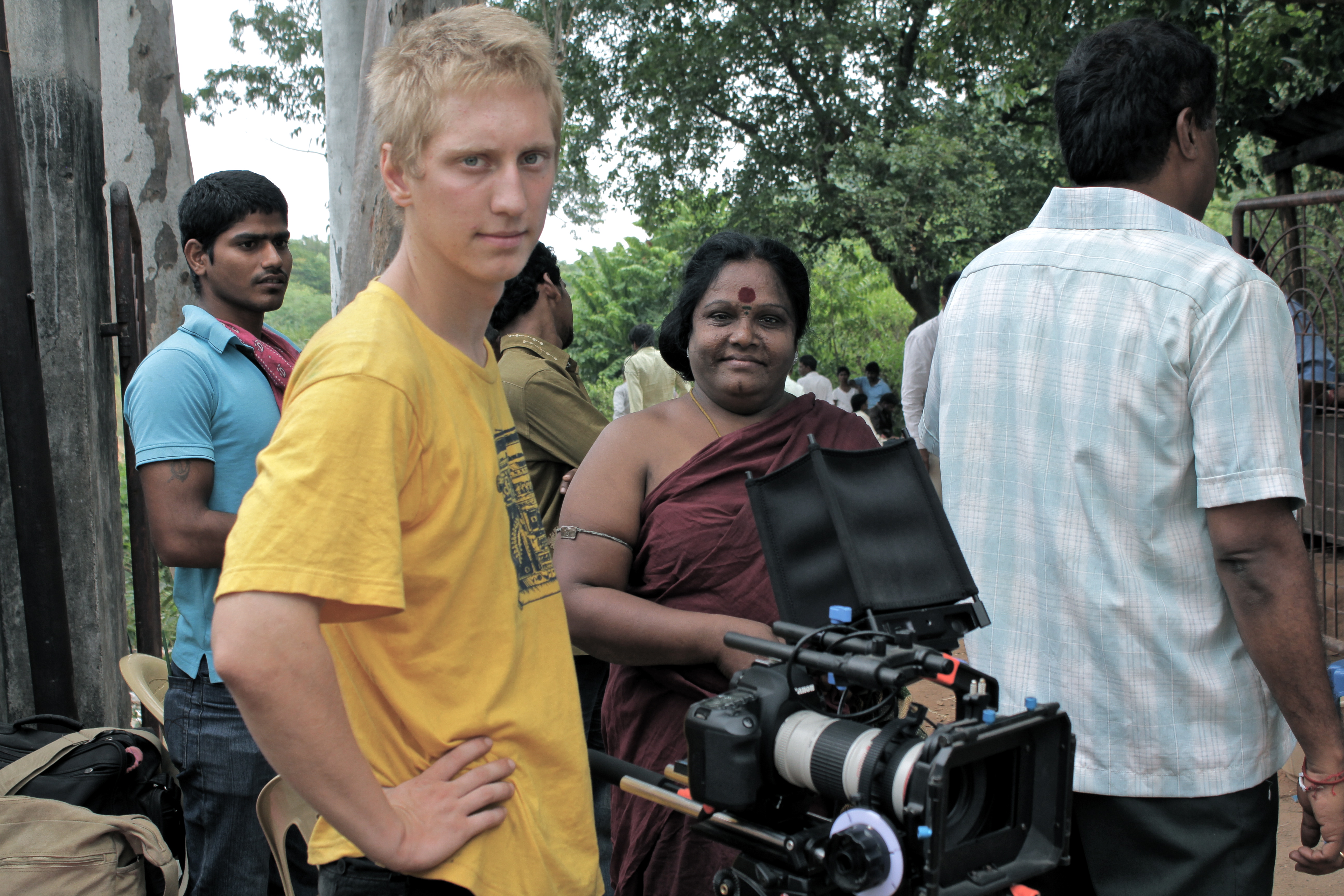 Paulius Kontijevas stands with his video camera surrounded by Indian cast and crew of a film.