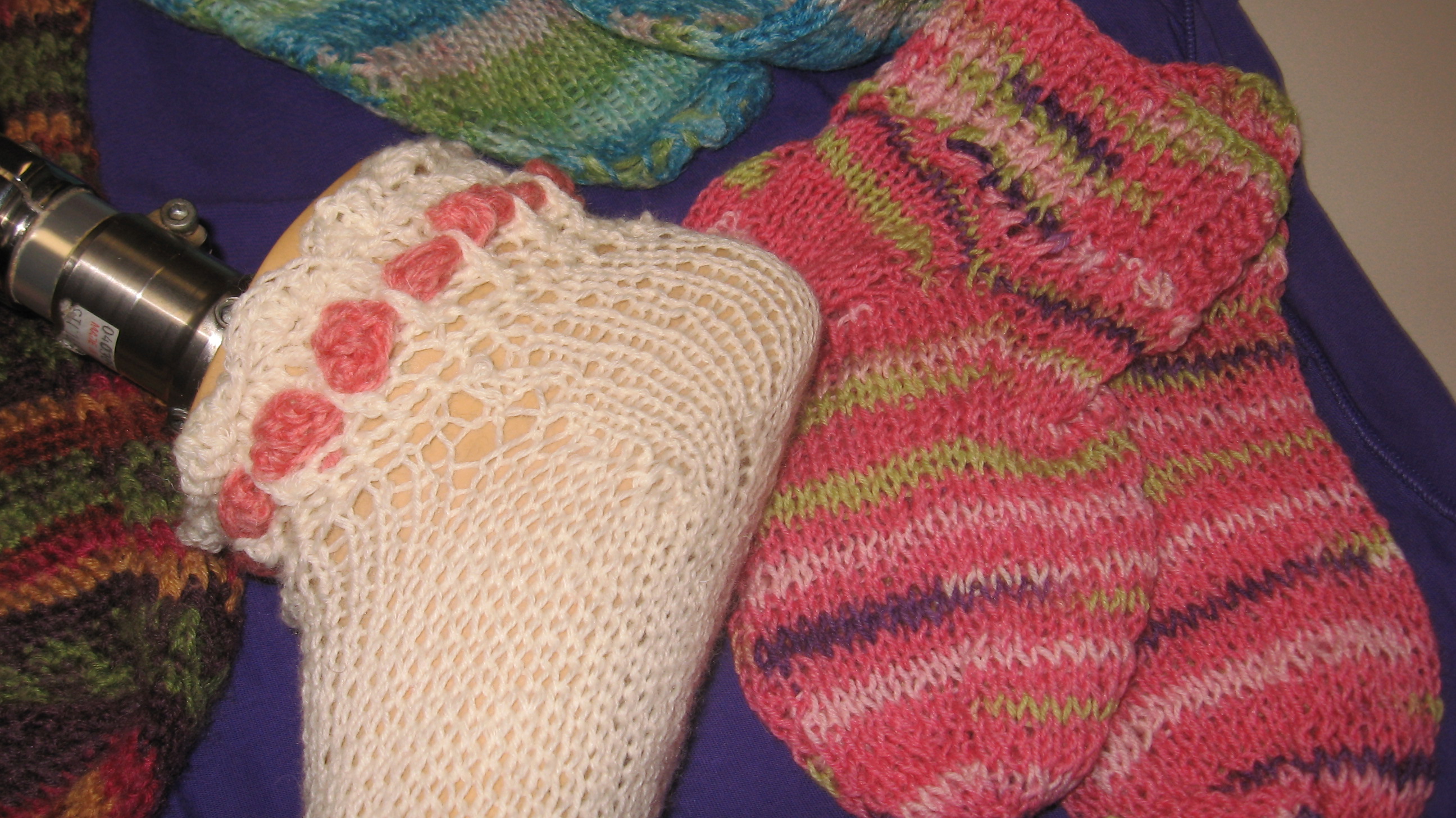 knitted socks A pair of bright, colorful hand knitted socks on display. Also, a pale pink knitted sock with a dark pink border is displayed on a prosthetic foot.