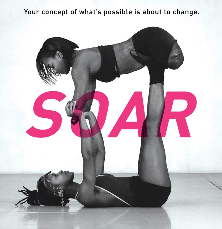 SOAR A black and white image of two female, African-American dancers with "SOAR" in large pink lettering and the sentence "Your concept of what's possible is about to change." One dancer lies on her back with her arms and legs facing up, holding aloft the second dancer, whose arms and legs are shortened from being amputated early in life.