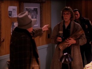 Pete Martell points accusingly at The Log Lady, who holds her log and a jar of burnt engine oil. Deputy Tommy Hawk Hill is behind her.