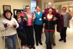 Seven smiling people stand together holding up their new handmade earrings.